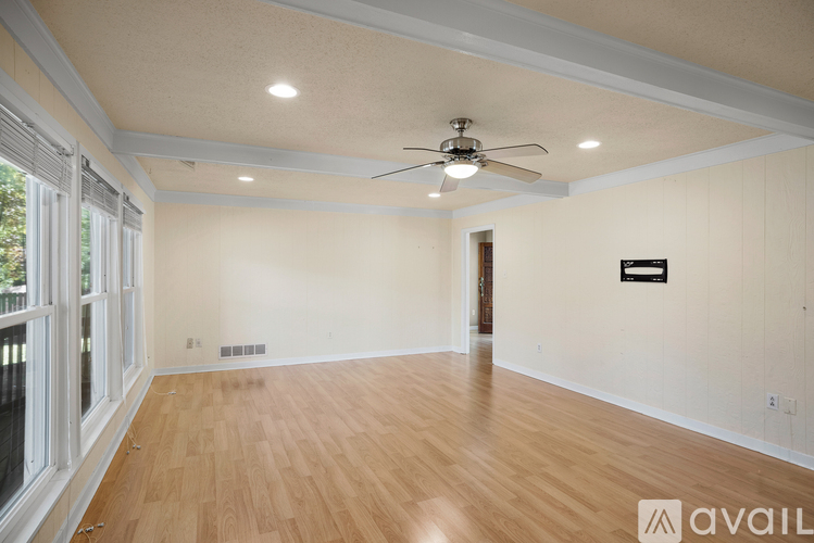 A spacious room with wooden floors and a ceiling fan.