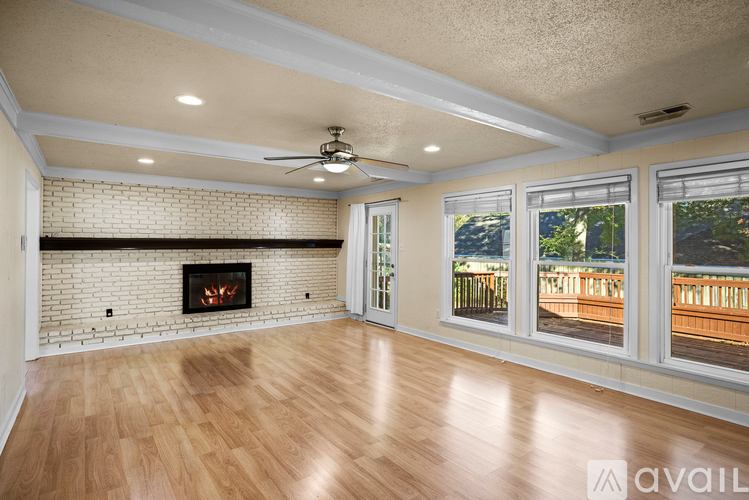 A spacious living room with a fireplace and a ceiling fan.