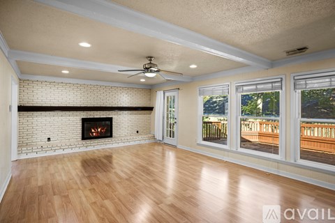 A spacious living room with a fireplace and a ceiling fan.