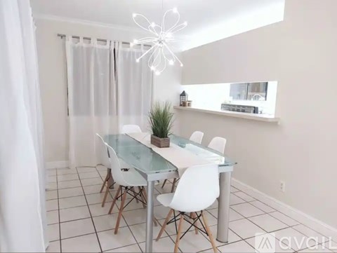A dining room with a glass table and white chairs.