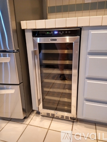 A stainless steel oven with a digital display is built into a kitchen cabinet.