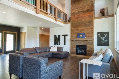 A living room with a grey couch and a fireplace.