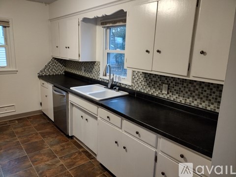 A kitchen with black countertops and white cabinets.