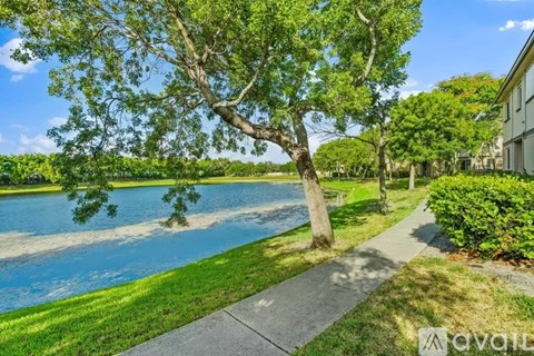 A tree stands in front of a house with a lake in the background.