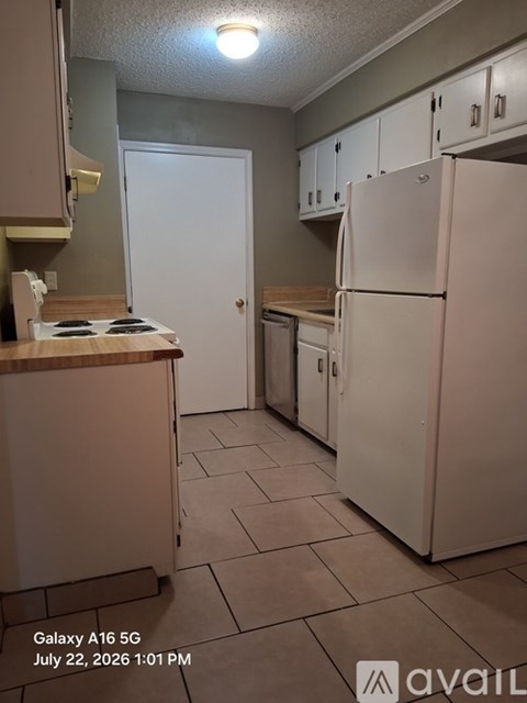 A kitchen with a white refrigerator and a white door.