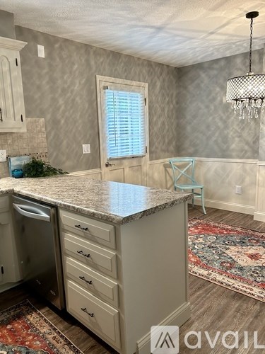 A kitchen with a granite countertop and a rug on the floor.