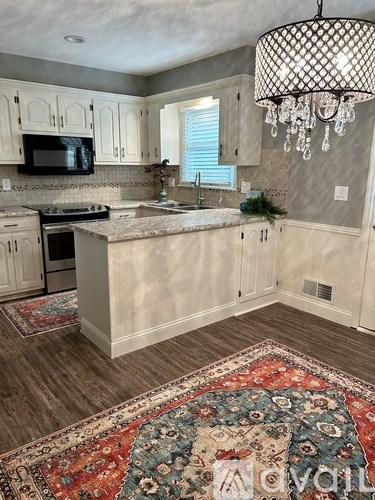 A kitchen with a rug on the floor and a chandelier hanging from the ceiling.