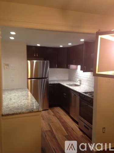 A kitchen with a refrigerator, sink, and wooden floors.