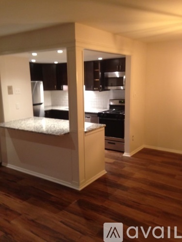 A kitchen with a white countertop and wooden floors.