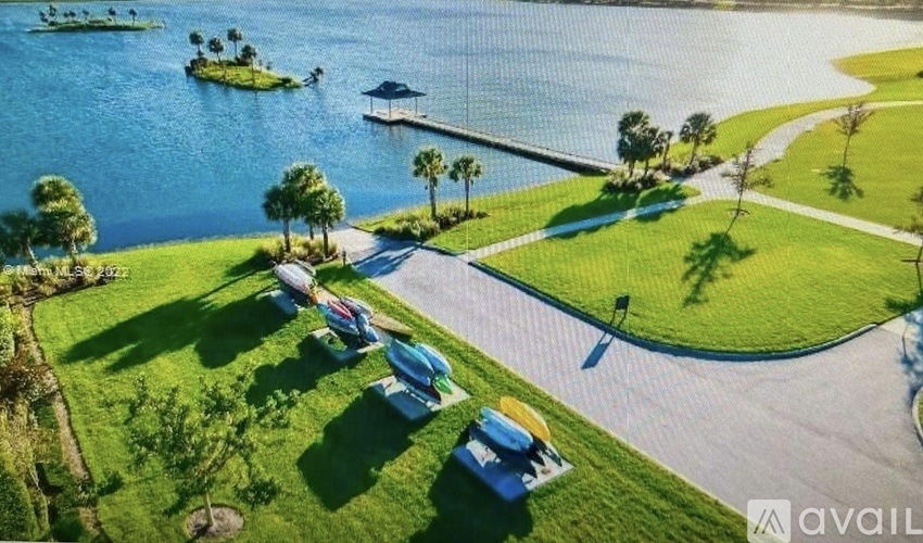 A serene lakeside scene with a gazebo, boats, and a picnic area.