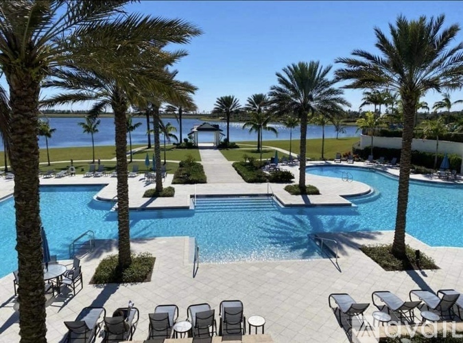 A pool surrounded by palm trees and lounge chairs.