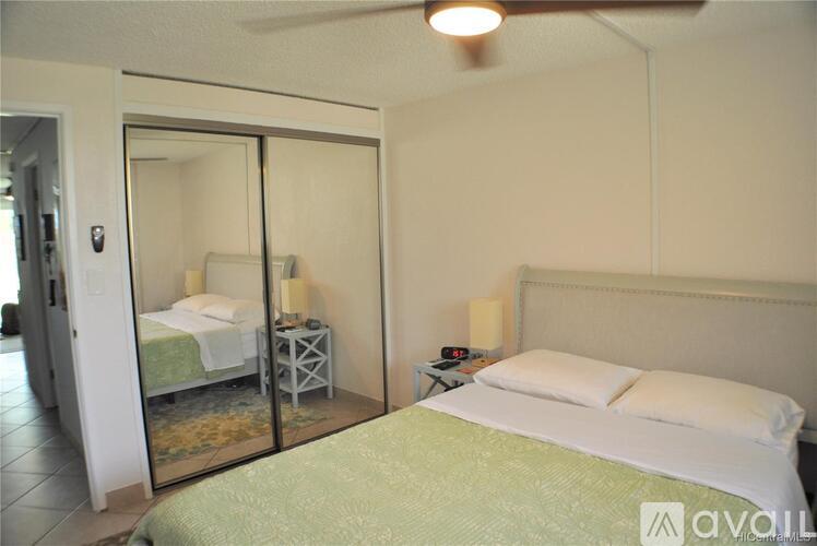 A bedroom with a bed, a nightstand, and a ceiling fan.