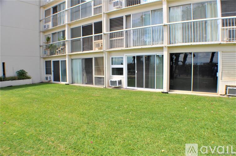 A grassy area in front of a building with balconies.