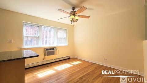 A room with a ceiling fan and wooden flooring.