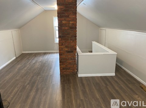 A room with a brick pillar and wooden flooring.