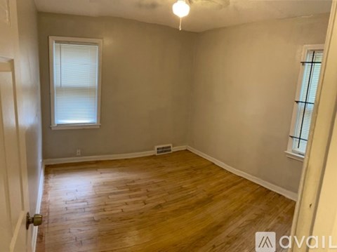 A room with wooden flooring and a window with blinds.