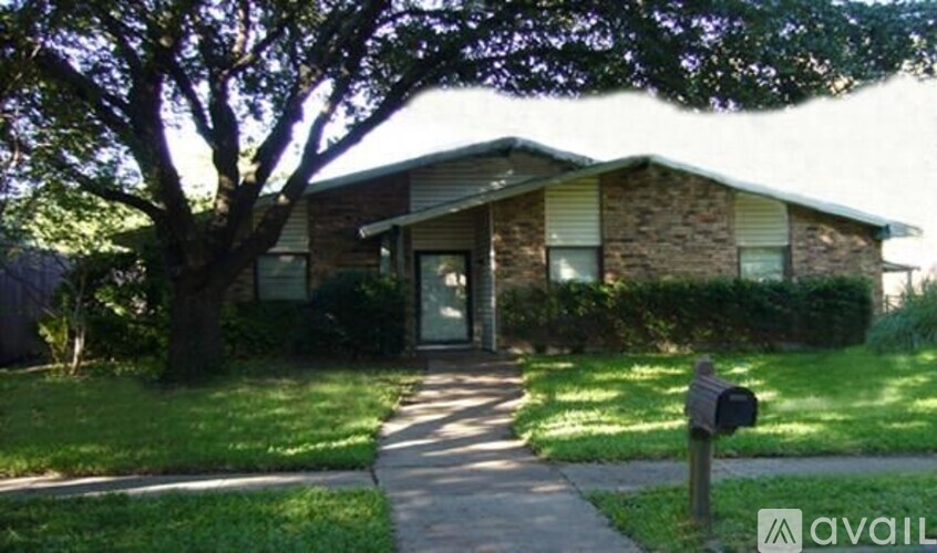 A house with a tree in front and a mailbox on the side.