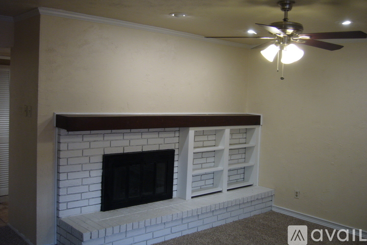 A fireplace with a white mantle and a fan on the ceiling.