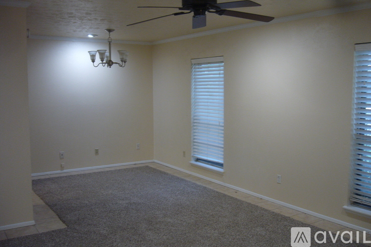 A room with a carpeted floor, a ceiling fan, and a chandelier.