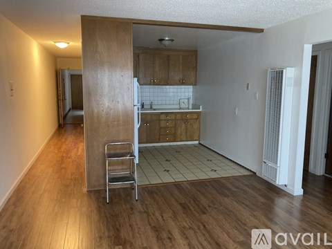 A kitchen area with a wooden floor and white walls.