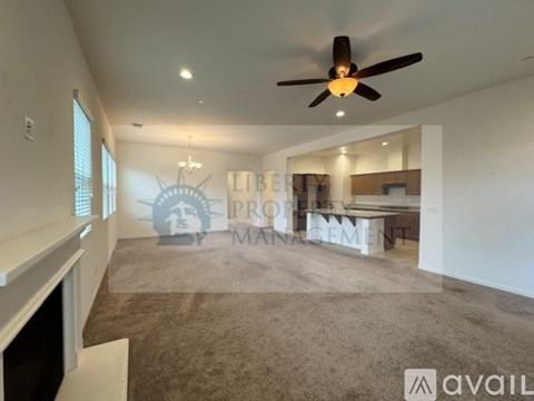A spacious living room with a fireplace and a ceiling fan.
