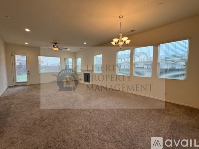A spacious room with a carpeted floor and a chandelier hanging from the ceiling.