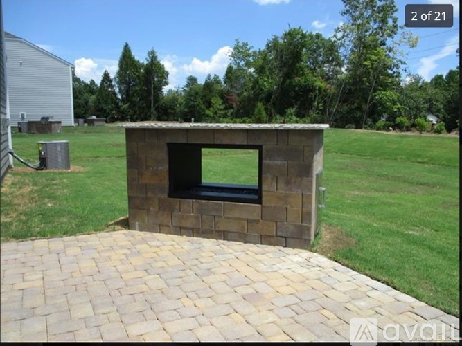 A brick structure with a black window is in the middle of a grassy area.