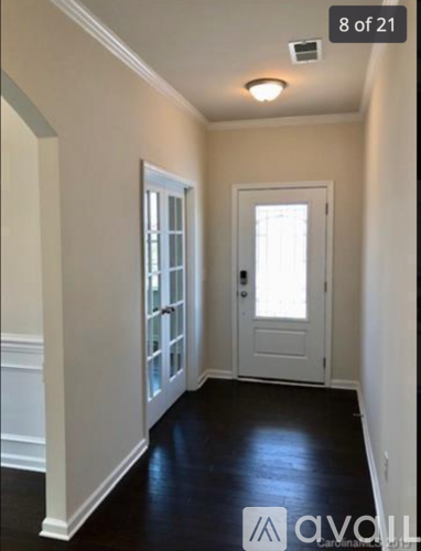 A hallway with a white door and a window.