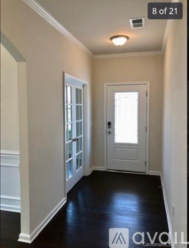 A hallway with a white door and a window.