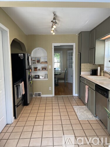 A kitchen with a black fridge and a tile floor.