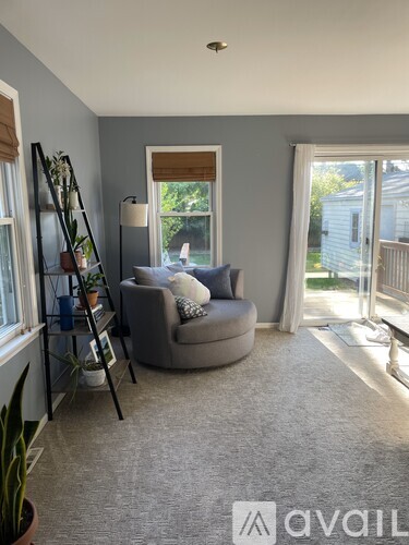 A living room with a grey couch and a ladder.