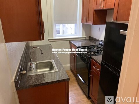 A kitchen with brown cabinets and a black refrigerator.