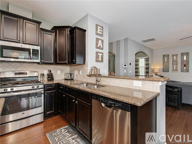 A modern kitchen with dark brown cabinets and stainless steel appliances.