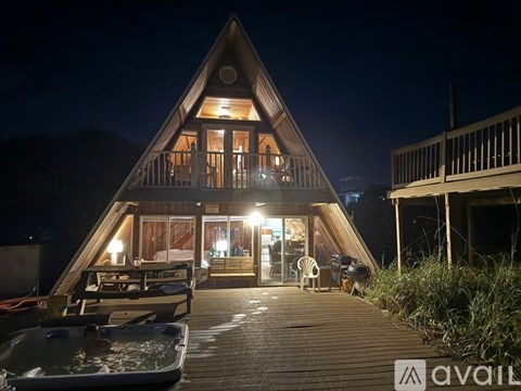 A wooden cabin with a hot tub in front at night.