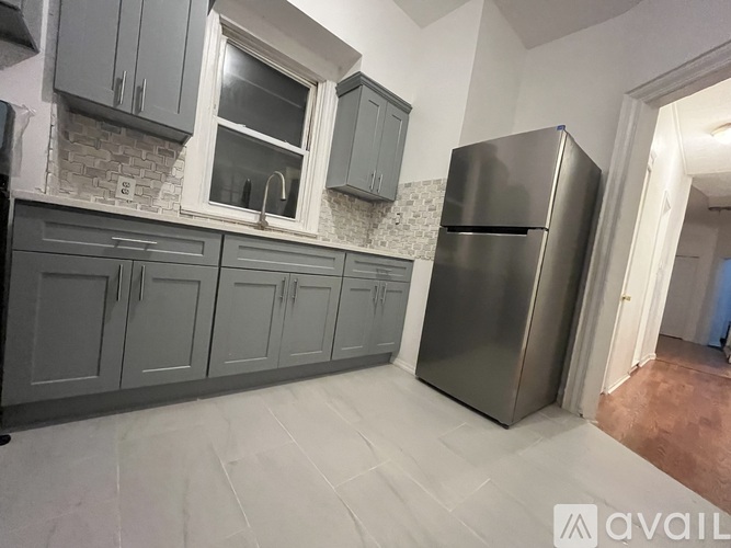 A kitchen with grey cabinets and a stainless steel refrigerator.