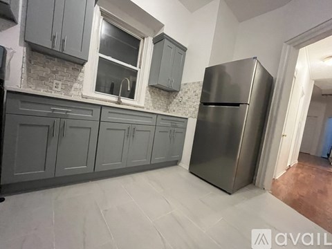 A kitchen with grey cabinets and a stainless steel refrigerator.