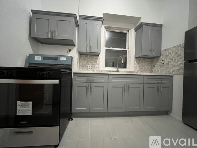 A kitchen with grey cabinets and a black oven.