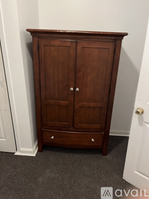 A wooden wardrobe stands in a room.