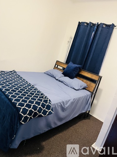 A bed with a blue and white patterned blanket and a wooden headboard.