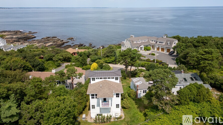 A bird's eye view of a house surrounded by trees and a body of water.