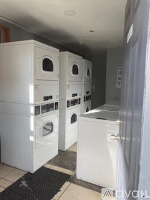A row of white front loading washing machines in a laundromat.