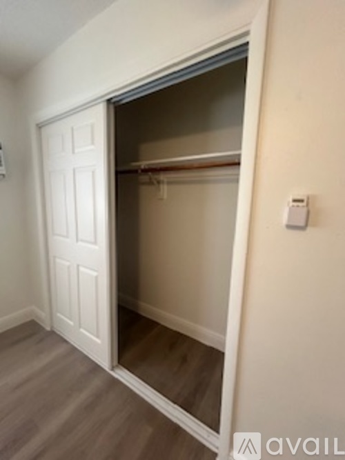A white door is open to a room with a wooden floor.