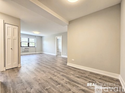 A spacious room with wooden flooring and a door on the left.