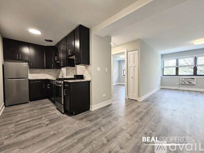 A kitchen with black cabinets and a refrigerator.