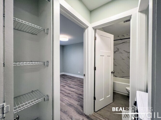 A white closet with shelves and a white door leading to a bedroom.