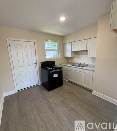 A kitchen area with a black trash bin and a white door.