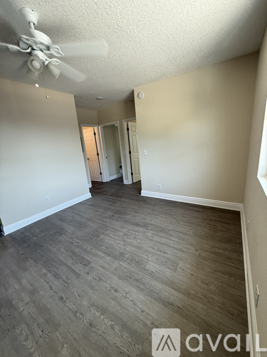 A room with a ceiling fan and wood flooring.