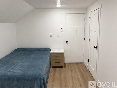 A bedroom with a bed, nightstand, and two doors.