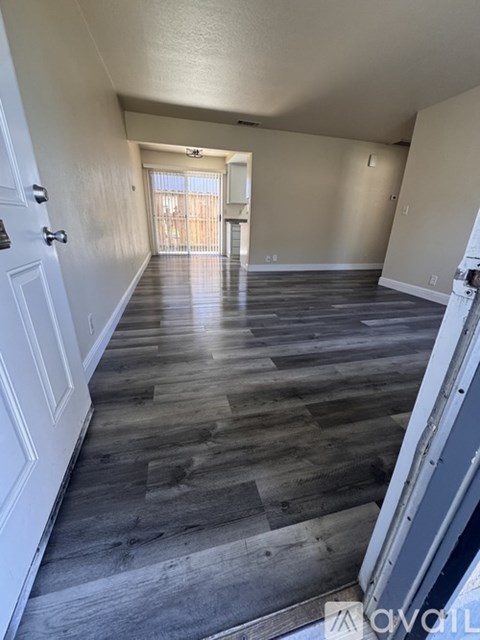 A long hallway with wood flooring and white walls.