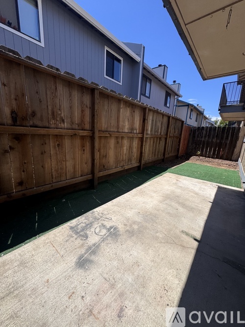 A backyard with a wooden fence and a green patch of grass.